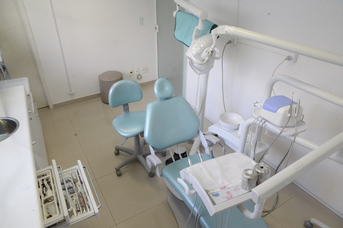 Cadeira odontológica, mocho e equipamento na sala de atendimento
